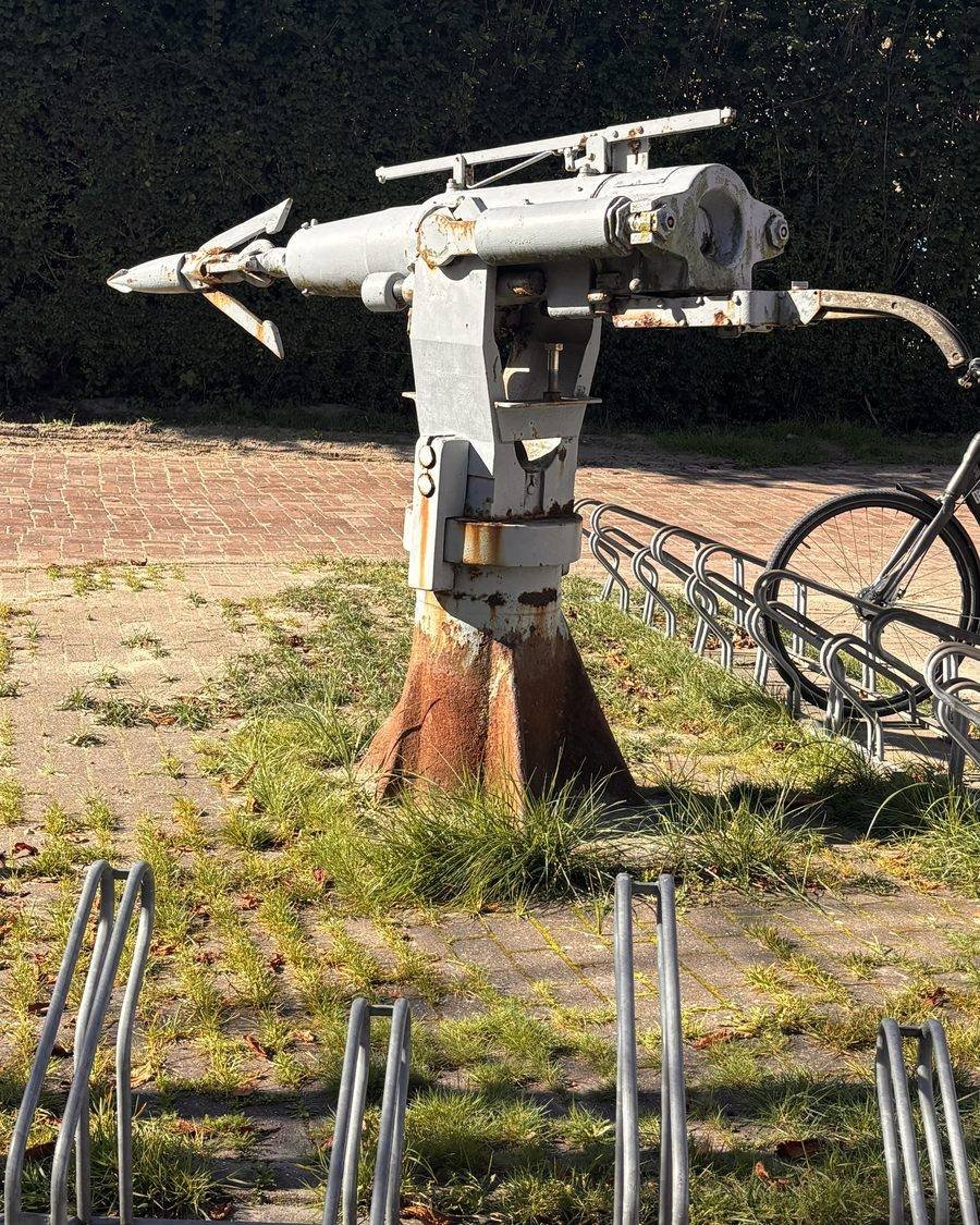 An old harpoon gun mounted on a post next to a row of bicycle racks